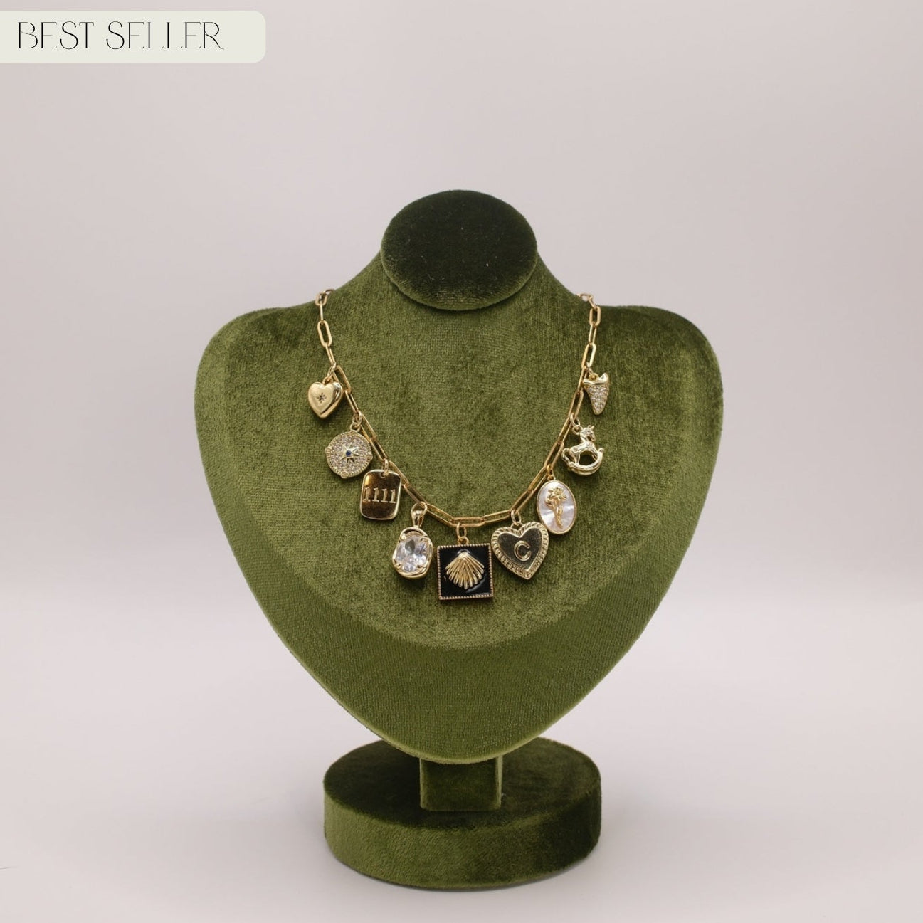 Necklace with heart and round pendants on a green velvet stand against a white background
