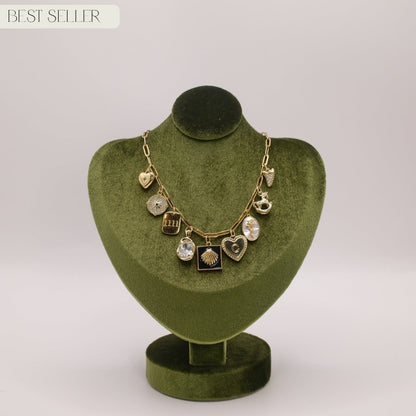 Necklace with heart and round pendants on a green velvet stand against a white background